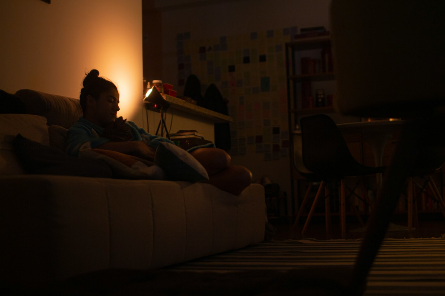 Frau kuschelt mit einem Haustier auf einer weißen Couch.