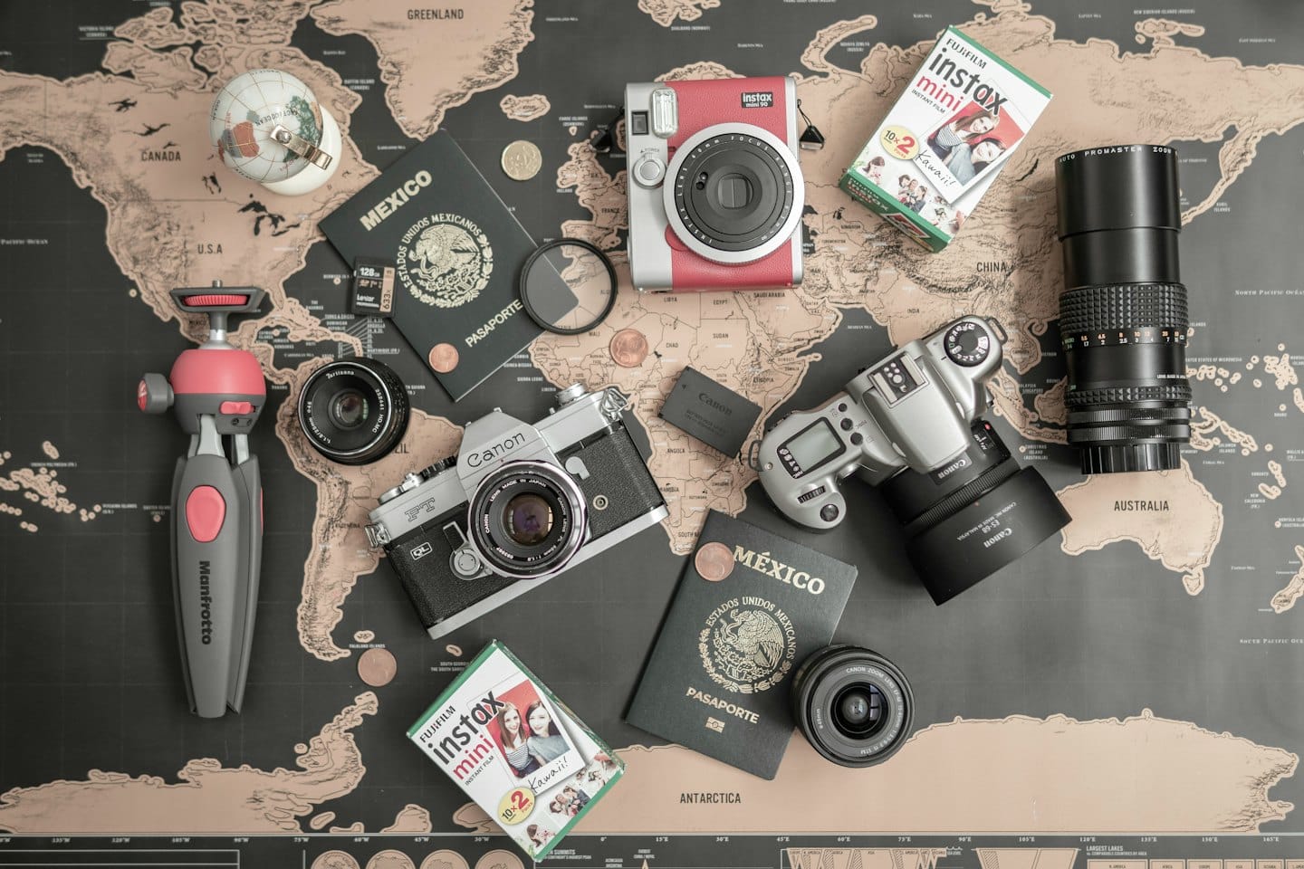 Reise- und Fotoausrüstung auf einer Weltkarte arrangiert.